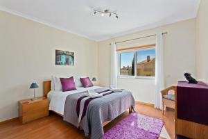 - une chambre avec un lit doté d'oreillers violets et d'une fenêtre dans l'établissement OPomar at Cabanas by Cara Rentals, à Cabanas de Tavira