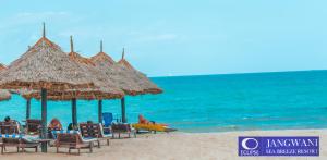 a beach with chairs and umbrellas and the ocean at Best Western Jangwani Sea Breeze Resort in Dar es Salaam