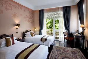 a hotel room with two beds and a window at Ping Nakara Boutique Hotel And Spa in Chiang Mai