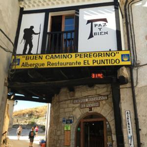 a building with a sign on the side of it at Albergue El Puntido in Hontanas