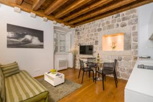 sala de estar con mesa y pared de piedra en Nije Preša Apartments, en Dubrovnik
