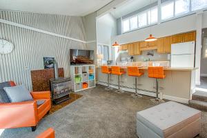 a living room with orange chairs and a kitchen at Gold Camp Gold Pan Condo: On Shuttle Route in Breckenridge