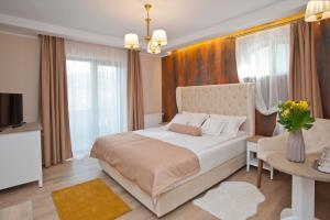 a bedroom with a large white bed and a table at Uphill Residence in Sinaia