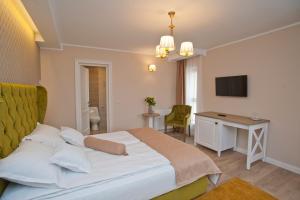una camera con letto, scrivania e TV di Uphill Residence a Sinaia