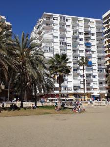 un gran edificio blanco en la playa con palmeras en MÁLAGA CENTER, MALAGUETA BEACh, en Málaga