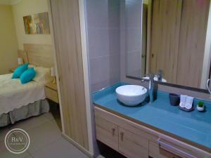 baño con lavabo con espejo y cama en R&V Apartments, en Santiago