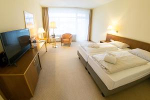 ein Hotelzimmer mit 2 Betten und einem Flachbild-TV in der Unterkunft Hotel Alexandersbad in Bad Alexandersbad