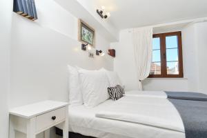 a white bedroom with a bed and a window at Apartments Zebra in Tivat