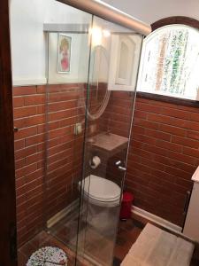 a bathroom with a toilet and a glass shower at CHALÉ TANAJURA - MONTE VERDE - Lareira, aconchego e WiFi in Monte Verde