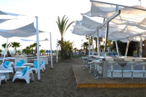 a beach with tables and chairs and white umbrellas at Sandy Beach Hotel & Spa - ex Sentido in Larnaca