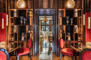 a dining room with wood paneling and red chairs and tables at Villa Eden a member of Leading Hotels of the World in Merano