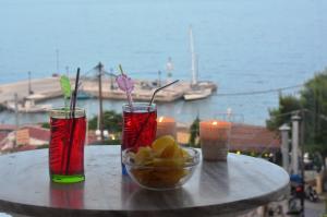 a table with two cocktails and a bowl of fruit at Hotel Liberty 1 in Agia Marina Aegina