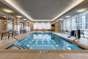 a pool in a hotel with tables and chairs at Cambria Hotel Omaha Downtown in Omaha