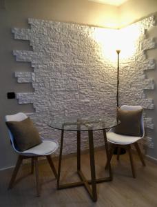 a glass table and two chairs in front of a brick wall at Pretoria House in Potenza