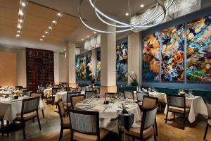 a dining room with tables and chairs and a large painting at Grande Colonial La Jolla in San Diego