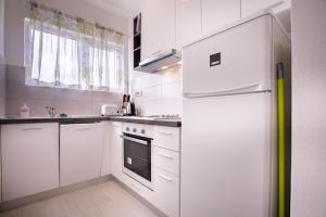 a kitchen with white cabinets and a refrigerator at Apartments Marija - good location in Supetarska Draga