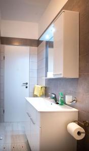 a white bathroom with a sink and a mirror at Apartments Marija - good location in Supetarska Draga