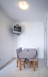 a dining room table with chairs and a tv on a wall at Apartments Marija - good location in Supetarska Draga