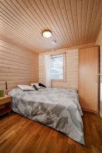 1 dormitorio con 1 cama en una habitación de madera en Luoman Hirvimökit, en Ähtäri