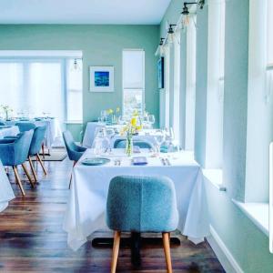 a dining room with a white table and blue chairs at Oar restaurant and Rooms in Doolin