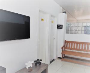 a living room with a flat screen tv and a bench at Villa Maragogi Hostel in Maragogi