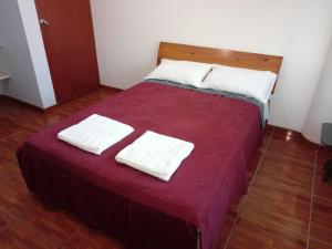 a red bed with two white towels on it at Hostal Sotillo in Ilo