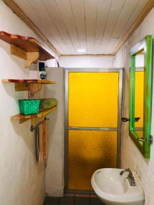 La salle de bains est pourvue d'une porte jaune et d'un lavabo. dans l'établissement Lindo Departamentito en Creel, à Creel