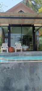 two white chairs sitting under a pavilion with a pool at Mook Tamarind Resort in Ko Mook