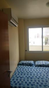 a bedroom with a blue bed with a window at Condomínio Solaris residencial Club in Ilhéus
