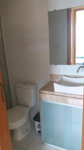 a white bathroom with a toilet and a sink at Condomínio Solaris residencial Club in Ilhéus