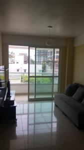 a living room with a couch and a large window at Condomínio Solaris residencial Club in Ilhéus