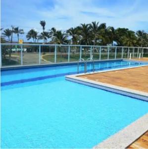 a large blue swimming pool with palm trees in the background at Condomínio Solaris residencial Club in Ilhéus