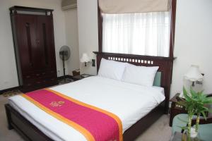 a bedroom with a large bed with a wooden headboard at Camela Hotel & Resort in Hai Phong