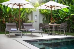 a patio with tables and umbrellas next to a pool at Trichada Tropical in Bang Tao Beach