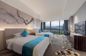 a hotel room with two beds and a tv at Huaqiang Plaza Hotel Shenzhen, Enjoy Complimentary Mini Bar & Night Snack, Add breakfast - enjoy complimentary afternoon tea in Shenzhen
