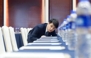 a boy sitting at a table in front of rows of chairs at Huaqiang Plaza Hotel Shenzhen, Enjoy Complimentary Mini Bar & Night Snack, Add breakfast - enjoy complimentary afternoon tea in Shenzhen