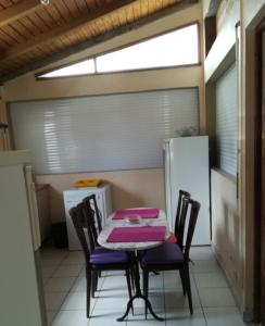 a table and chairs in a kitchen with a refrigerator at Villa bleue in Sainte-Anne