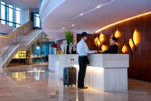 a man and a woman standing at a counter with a suitcase at Huaqiang Plaza Hotel Shenzhen, Enjoy Complimentary Mini Bar & Night Snack, Add breakfast - enjoy complimentary afternoon tea in Shenzhen