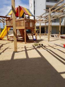 uma criança a brincar num parque infantil com uma estrutura de madeira em Departamento Familiar Linda Vista Condominio BordeMar Los Molles em Los Molles