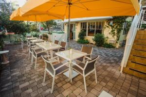 un gruppo di tavoli e sedie con ombrellone di Villa Italia South Beach a Miami Beach