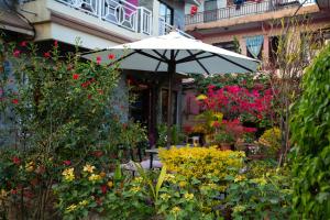 a white umbrella in a garden with flowers at Hotel Orchid in Pokhara