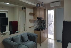 een woonkamer met een bank en een keuken bij Channel Stay @ Bassura City Apartment in Jakarta