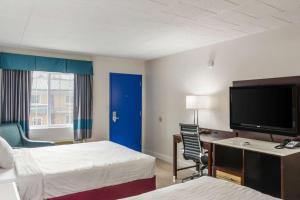 a hotel room with two beds and a flat screen tv at Rodeway Inn in Milford