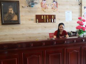 a woman sitting at a counter in a restaurant at Nhà Nghỉ BẢO CHÂU in Hà Tiên