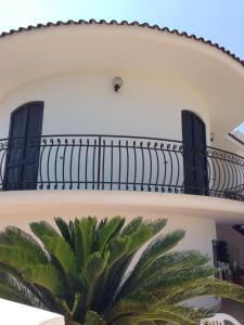 a house with a balcony and a palm tree at Villataty B&B in Castrignano del Capo