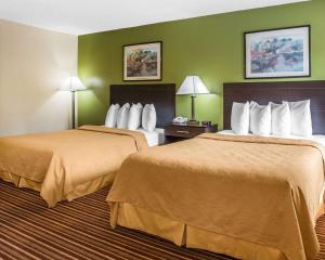 two beds in a hotel room with green walls at Suburban Studios in Augusta