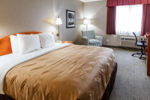 um quarto de hotel com uma cama grande e uma cadeira em Quality Inn Burlington near Hwy 34 em Burlington