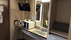 a bathroom with a microwave and a sink and a mirror at Aquatic Motor Inn in Taree