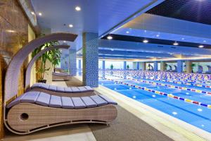 a large swimming pool with benches in a building at Empark Grand Hotel Hangzhou Bay Ningbo in Ningbo