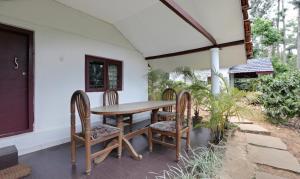 a wooden table and chairs on a patio at Itsy By Treebo - Jammabane Cottage With Mountain View in Madikeri